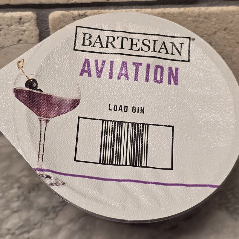 Bartesian Aviation cocktail pod with LOAD GIN instructions on travertine surface