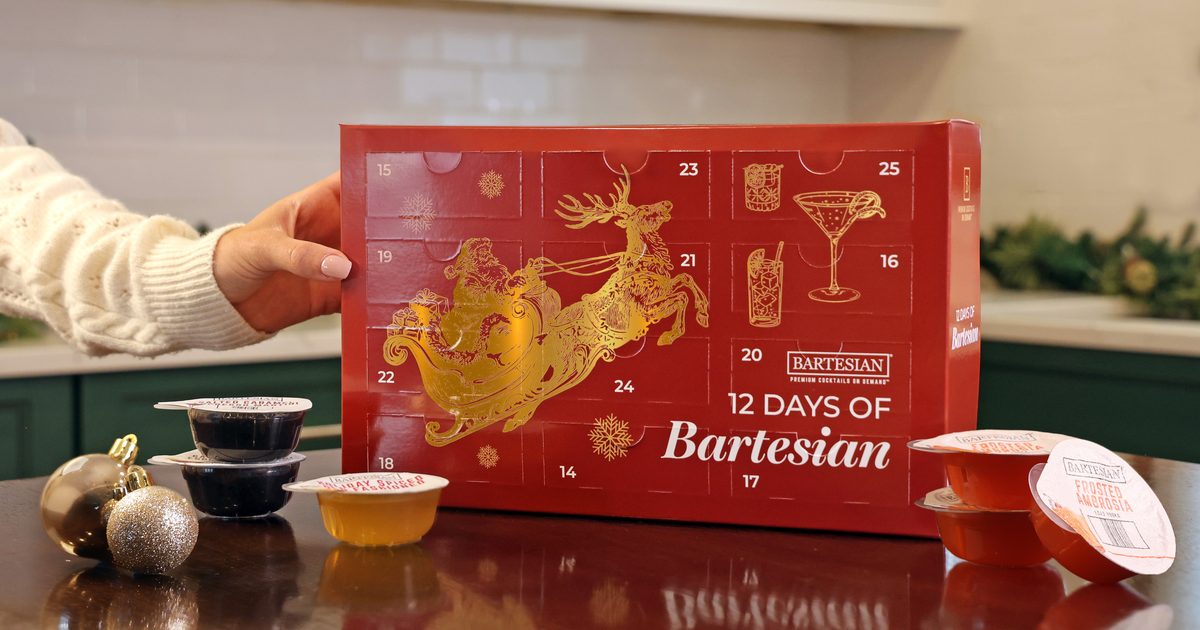 The 12 Days of Bartesian Advent Calendar box held on a kitchen counter with cocktail capsules and gold ornaments beside it