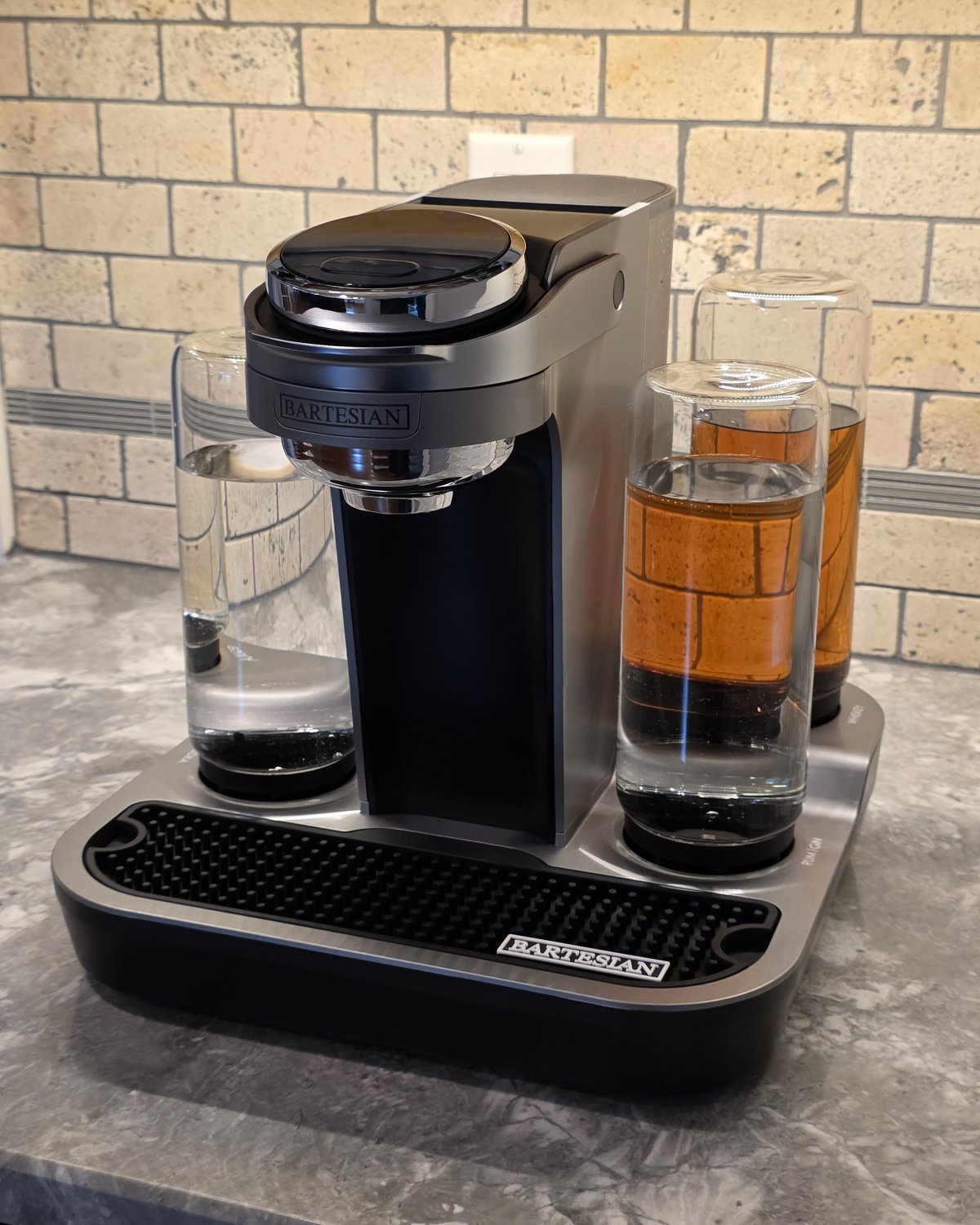 Bartesian Professional machine close-up with spirit bottles filled and loaded, water bottle on left and amber whiskey on right, drip tray with Bartesian logo visible