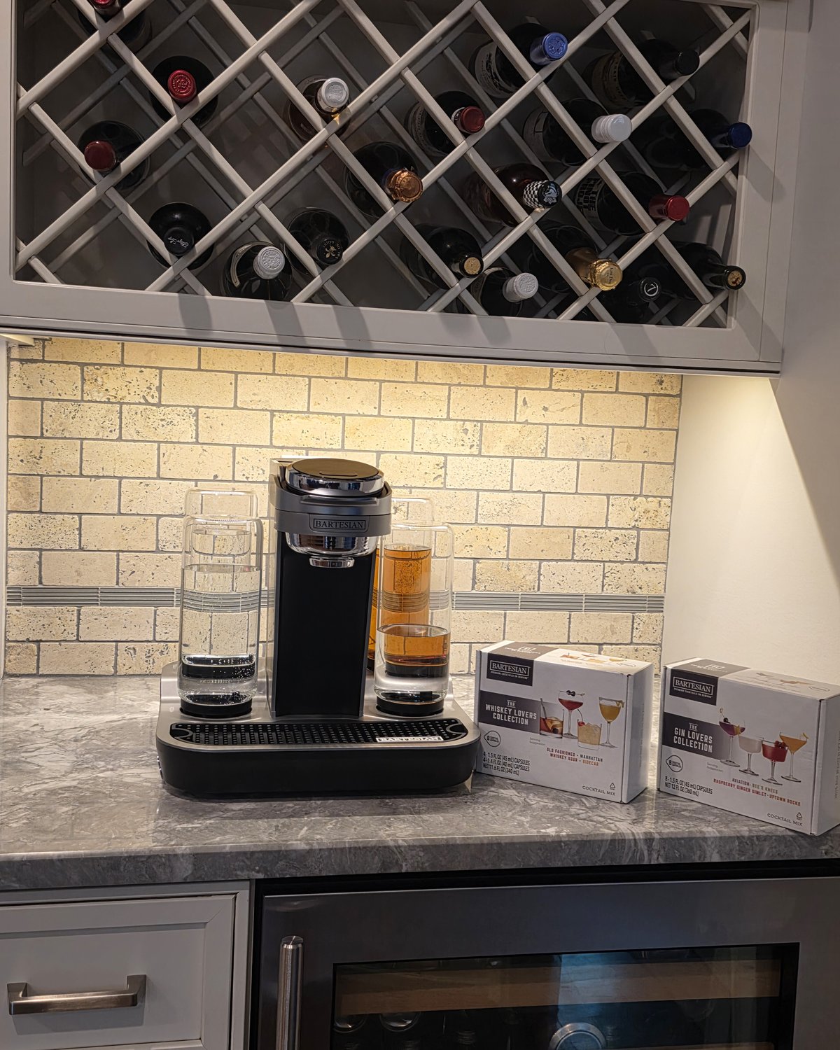Bartesian machine on the bar with both Whiskey Lovers Collection and Gin Lovers Collection pod boxes next to it, glassware around the machine showing real-world variety pack starting point