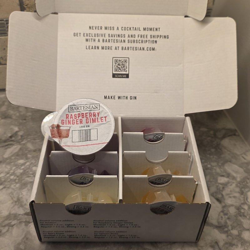 Open Bartesian Gin Lovers Collection pod box showing a Raspberry Ginger Gimlet capsule turned face-up, with alcohol volume guidelines visible on the box edge