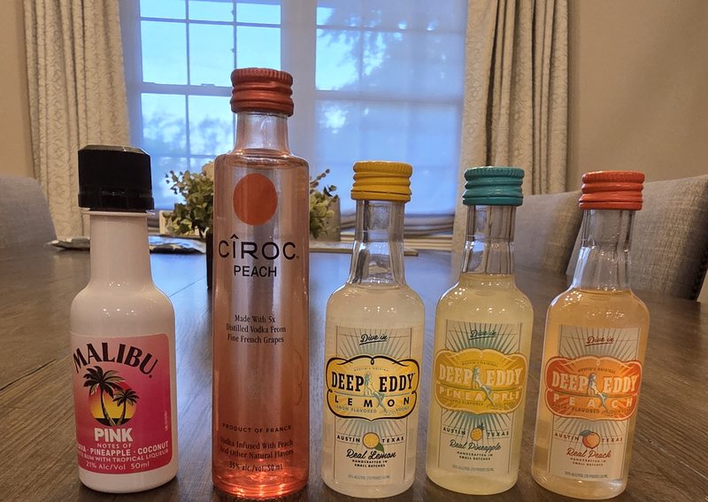 Five flavored spirit mini bottles including Deep Eddy Lemon lined up on a dining table