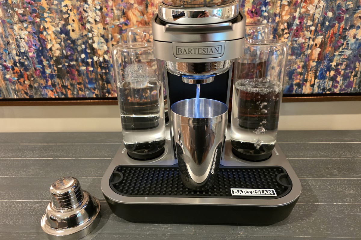 Bartesian cocktail machine pouring the Calamansi Daiquiri base into a stainless steel shaker, with rum bottle on the right and vodka bottle on the left