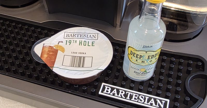 A Deep Eddy Lemon mini bottle beside a 19th Hole pod on a Bartesian machine drip tray
