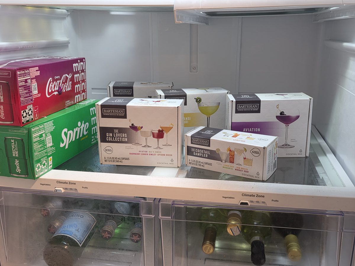 Bartesian cocktail pod boxes stored on a refrigerator shelf above the climate-zone drawers, the everyday spot that adds about two months to the printed date.