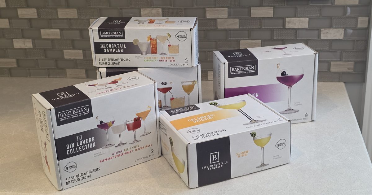 Several Bartesian cocktail pod boxes, including Aviation, the Gin Lovers Collection, the Cocktail Sampler, and Calamansi Daiquiri, arranged on a kitchen counter at room temperature.