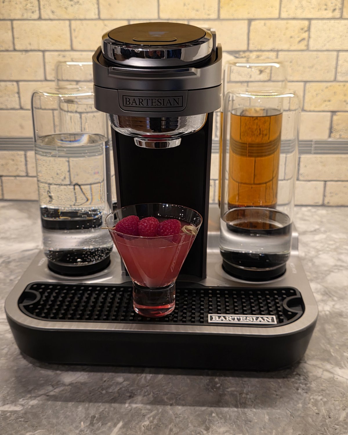 Bartesian Raspberry Ginger Gimlet cocktail in stemless martini glass garnished with three raspberries on the Bartesian machine