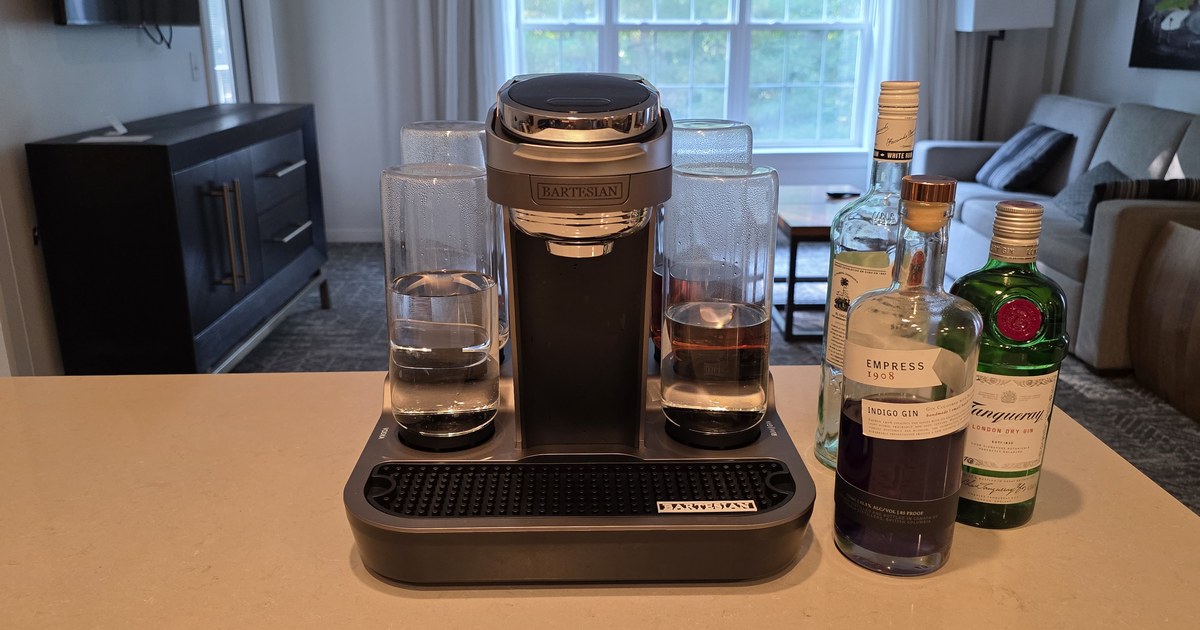 Bartesian Premier cocktail machine set up on a kitchen counter with gin and rum bottles beside it