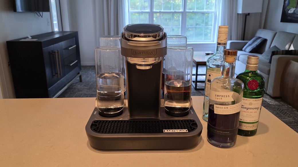 Bartesian Premier cocktail machine set up on a kitchen counter with Tanqueray gin, Empress 1908 gin, and Bacardi rum bottles beside it