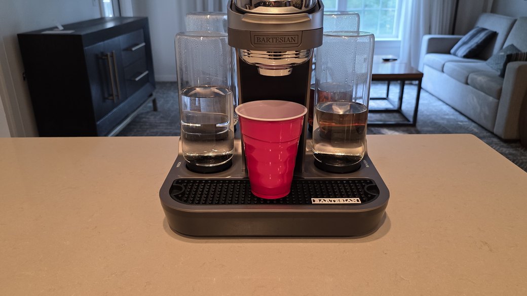 The Bartesian Premier dispensing a cocktail into a red Solo cup, with water glasses on either side, in the resort kitchen