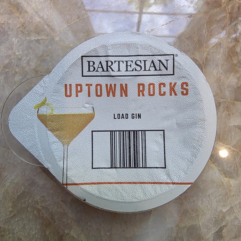 Bartesian Uptown Rocks pod, labeled Load Gin, resting on a marble counter