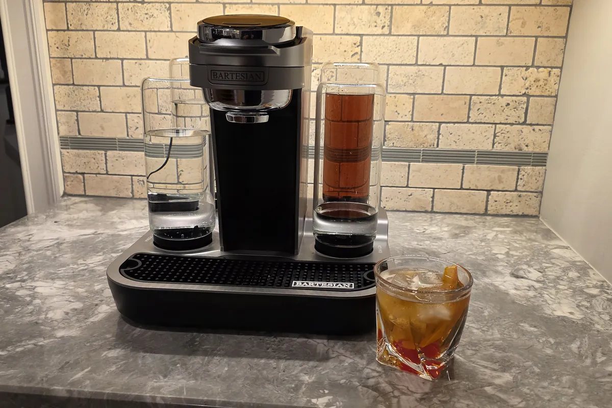 Bartesian cocktail maker on a kitchen counter beside a freshly made Old Fashioned in a rocks glass